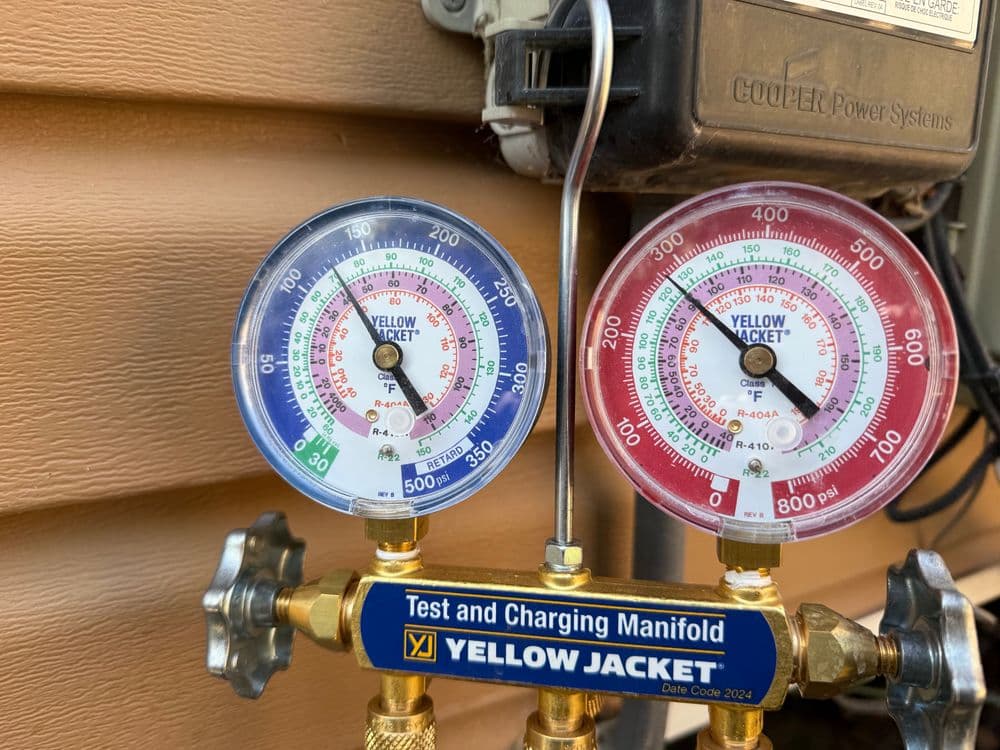 Manifold gauges displaying pressure and temperature readings for HVAC system maintenance.
